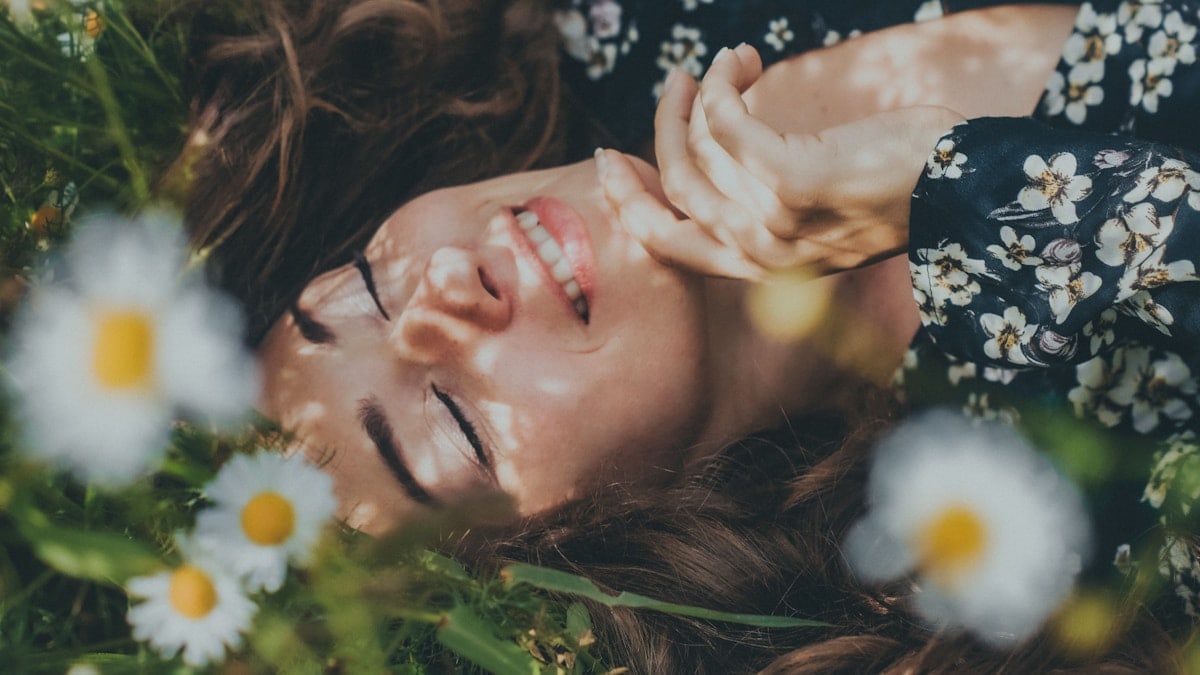 woman in black and white floral shirt lying on green grass field